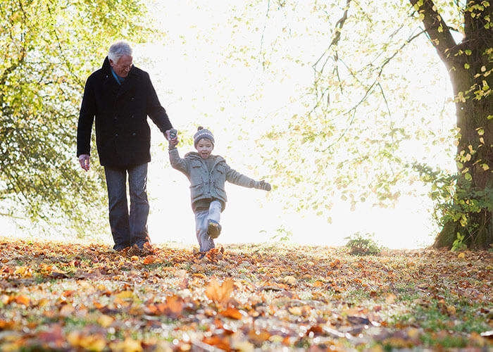  grandfather walking on a path with a grandson in autumn