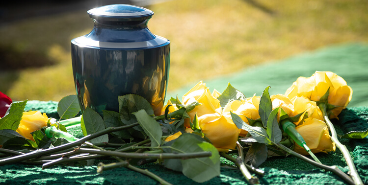 a ceramic burial urn and yellow roses