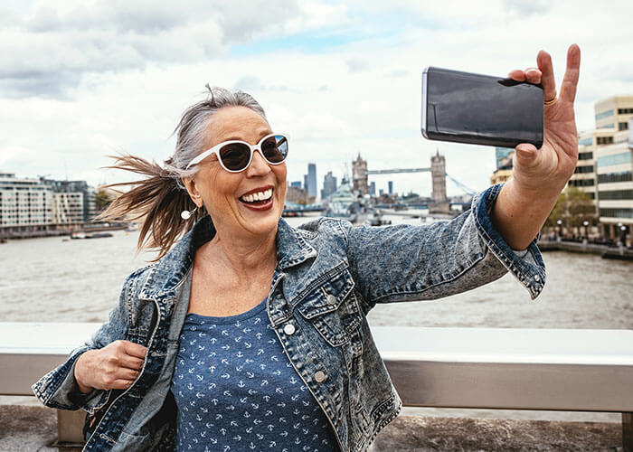 a middle aged woman taking a selfie for social media with a view of London in the background