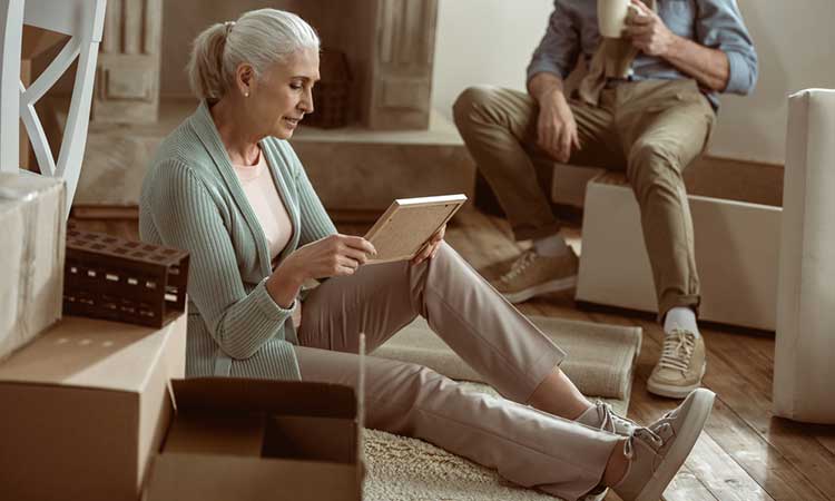mature lady sitting on the floor looking at a picture frame