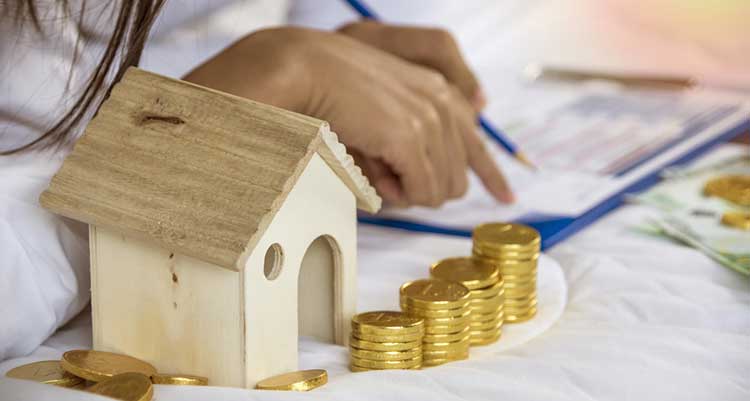 a wooden house with piles of pound coins around it