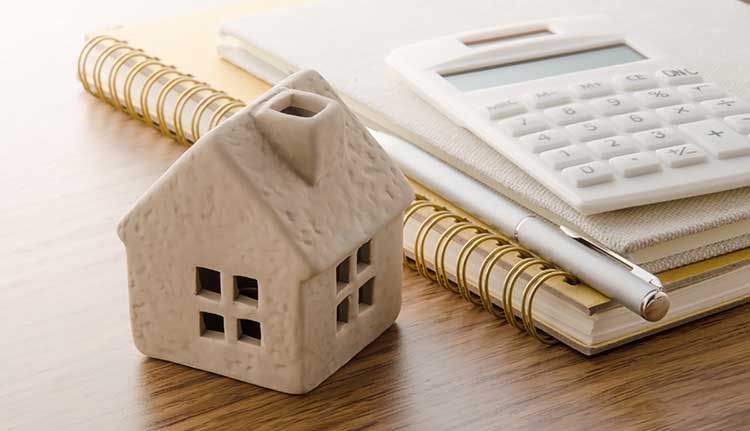 tiny house on a desk next to a notepad