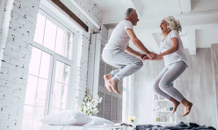 a couple jumping together on the bed