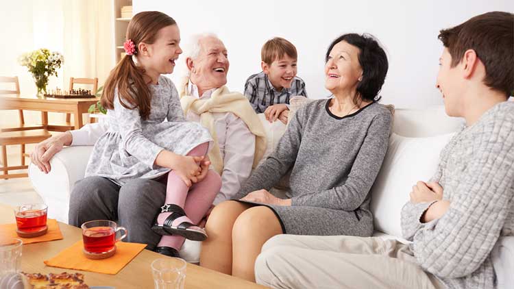 grandparents with their grandchildren sitting on a sofa laughing together