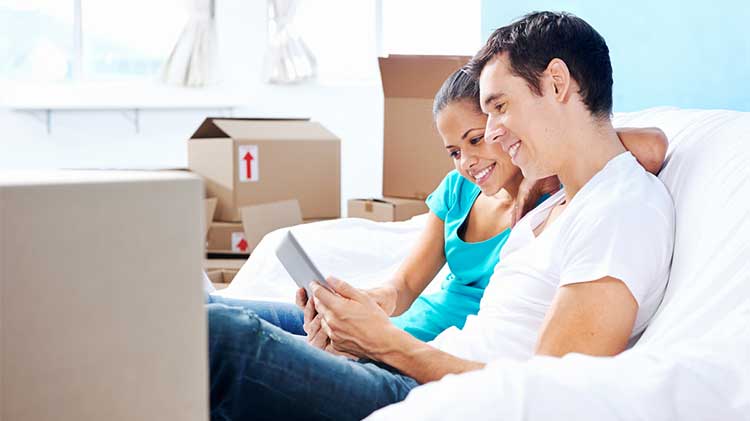 young couple sitting on a sofa surrounded by packing boxes