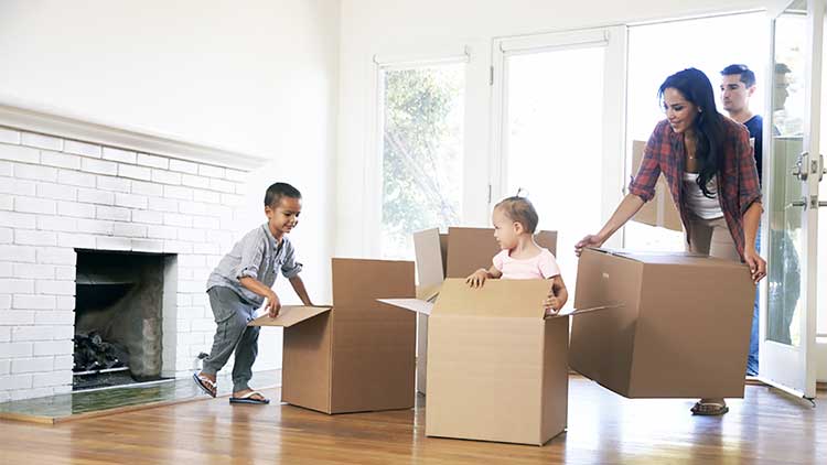 young family bringing boxes into a property