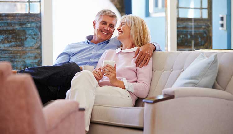 mature couple smiling and sitting on the sofa