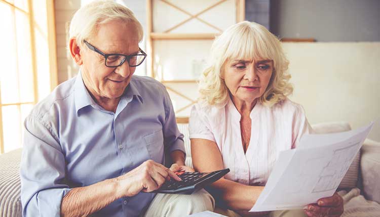 a mature couple looking at floor plans and calculating costs