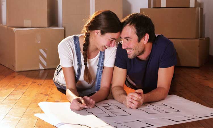 a young couple on the floor looking at floor plans