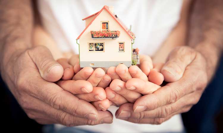 family holding a miniature house in their hands
