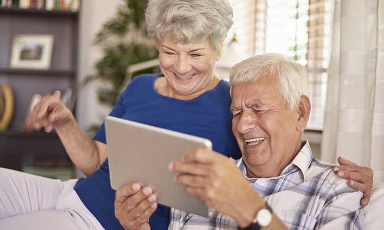 a mature couple laughing whilst looking at a tablet