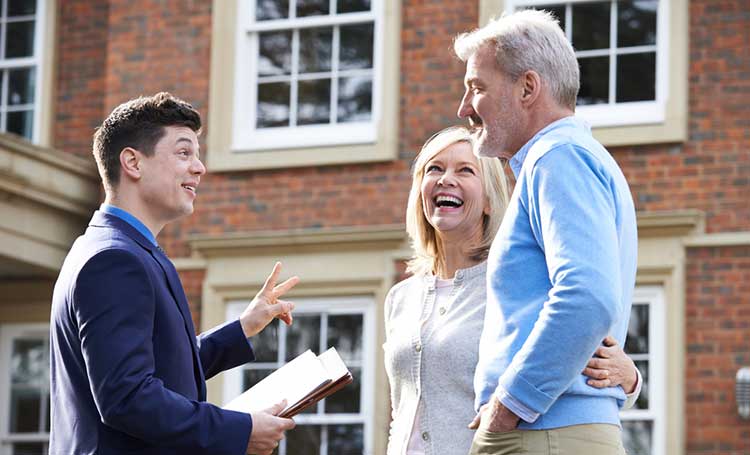 couple talking to an adviser outside of a house