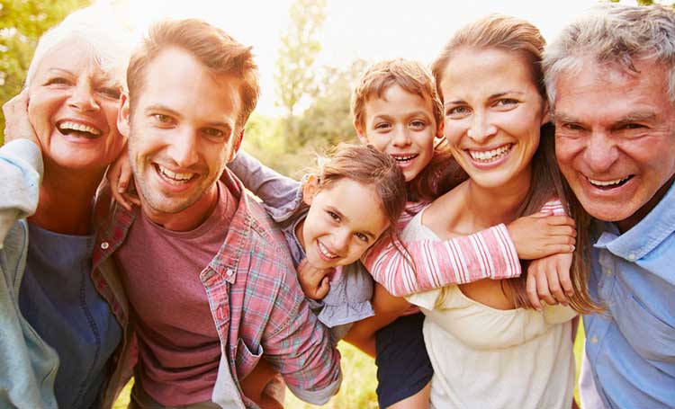 extended family hugging and smiling together into the camera