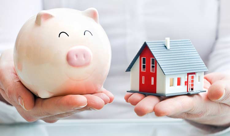 person holding a piggy bank and small house