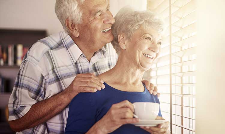 mature couple smiling together and looking out of the window