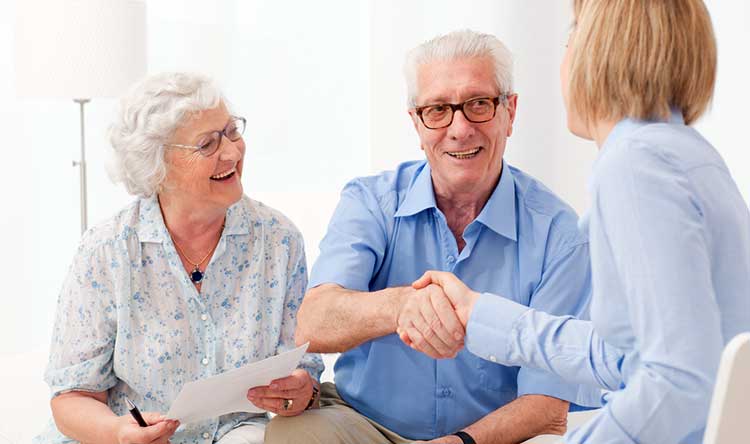 mature couple shaking hands with an adviser