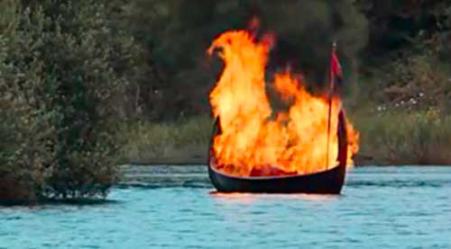 viking long boat on fire floating out to sea