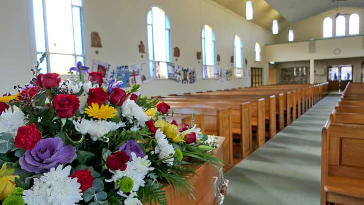 flowers on a coffin in an empty church