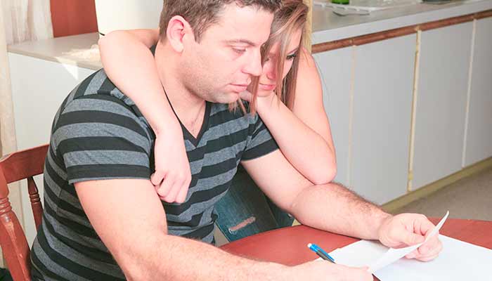 man and woman at kitchen table looking at a bill man and woman at kitchen table looking at a bill