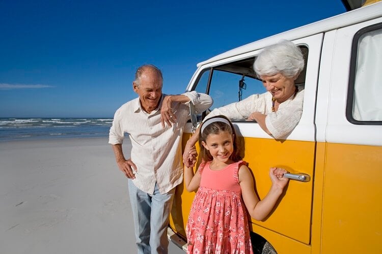 Grandparents smiling with granddaughter on beach