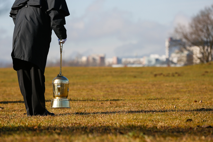 A person holding an urn to scatter ashes in a field