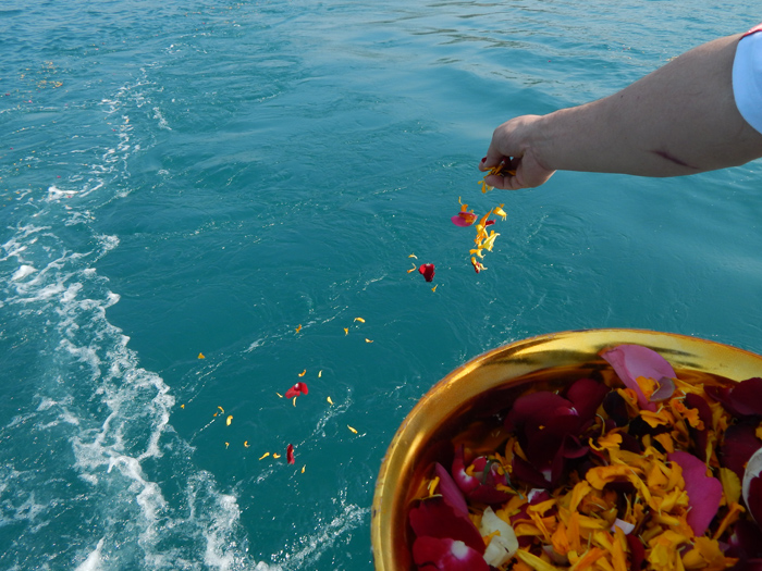 A person scattering ashes and petals into the sea