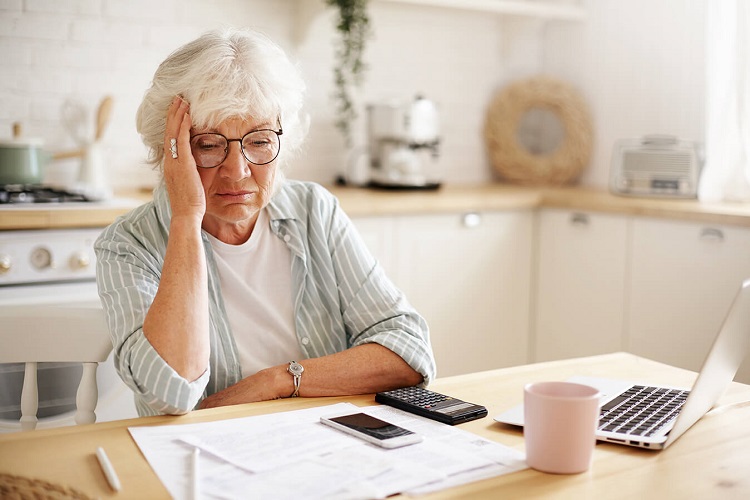 Elderly woman looking worryingly at paperwork