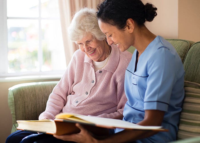 a carer showing a photo album to an elderly woman in their home