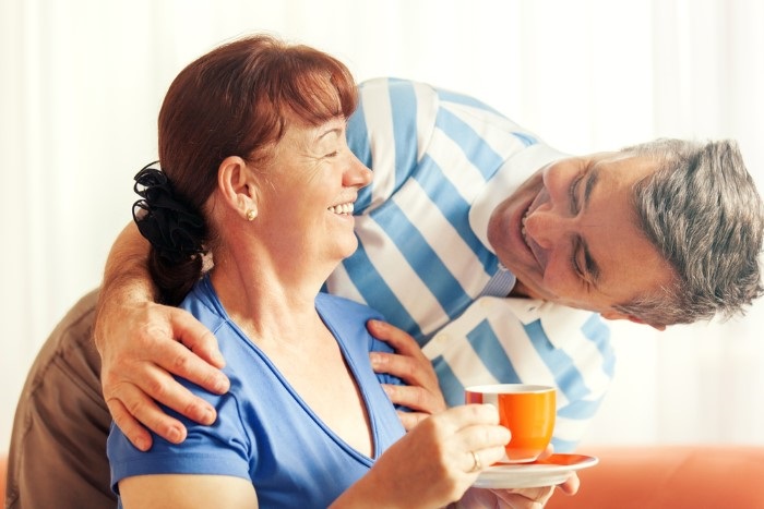a man and woman laughing whilst drinking tea