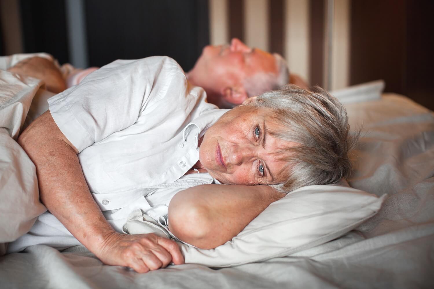 Upset woman in bed lying beside husband