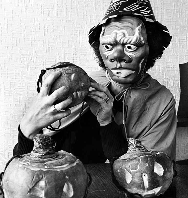 Person dressed as a witch holding a carved turnip