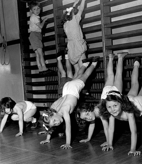 Children doing hand stands on wall bars in their knickers