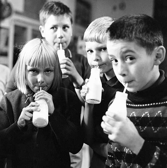 Children drinking milk from a bottle with a straw