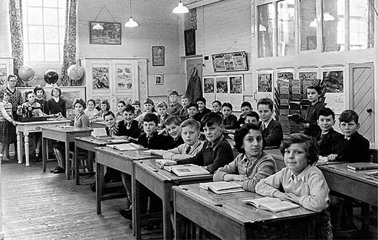 Group of school children sat around wooden desks