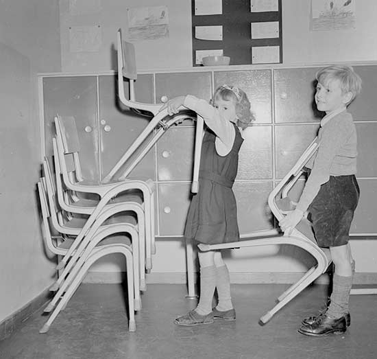 Young boy and girl stacking chairs after assembly