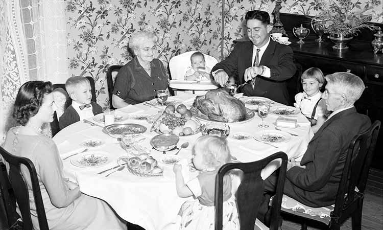 father carving the meat at a family dinner