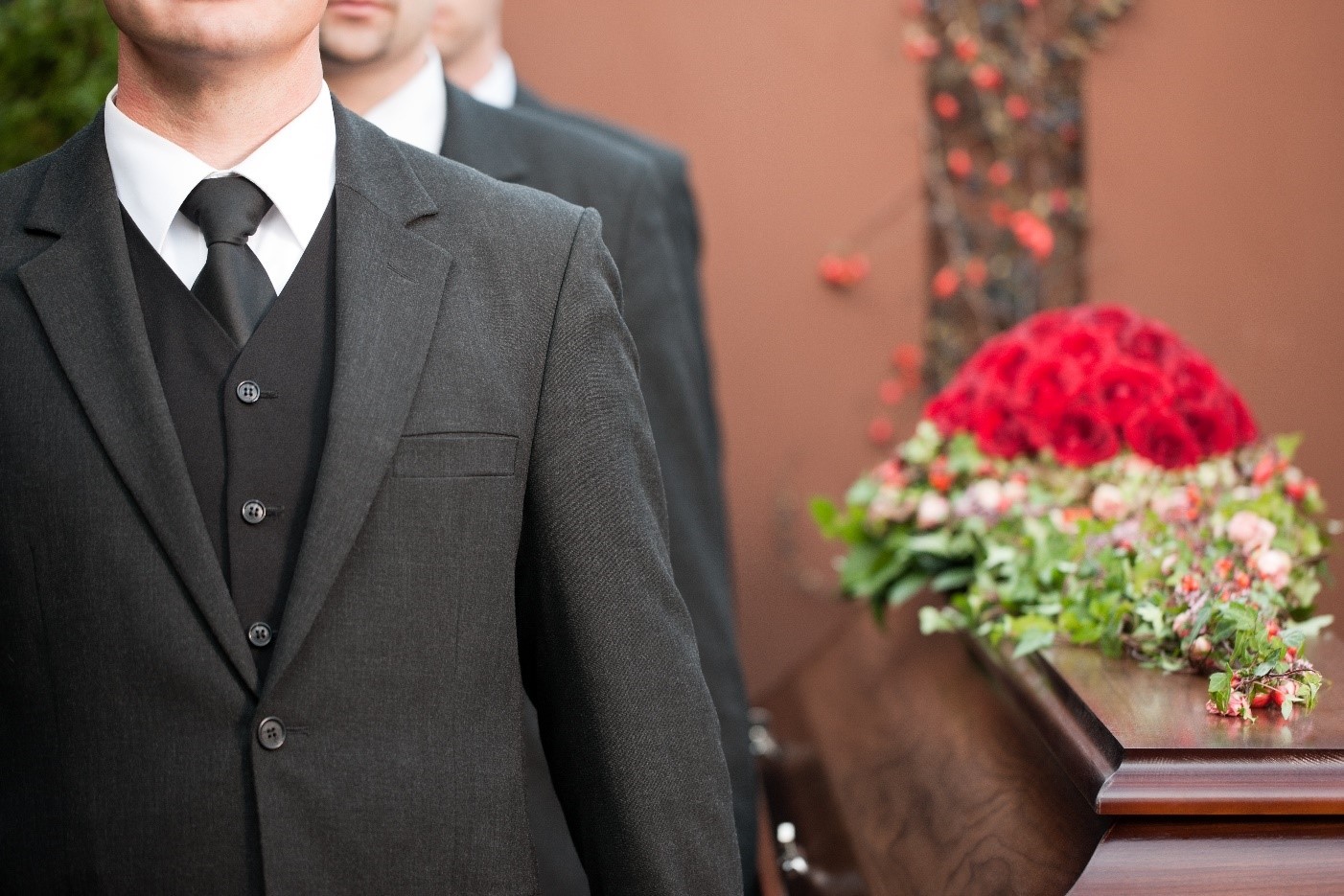 Man at a funeral next to a coffin.