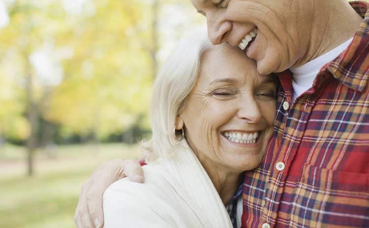 An over 50s couple hugging on a walk.