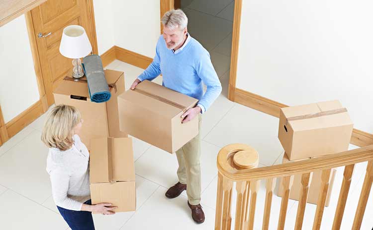 a mature couple in the hallway carrying packing boxes