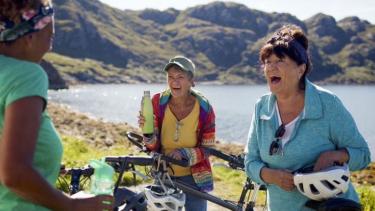 Mature lady cyclists stopping for a refreshments and laughing