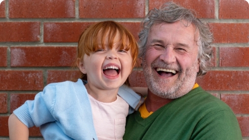 Granddad holding grandchild and smiling