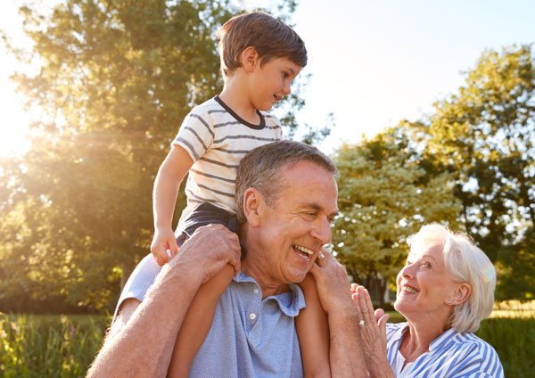 Granparent holding grandson on his shoulders outside