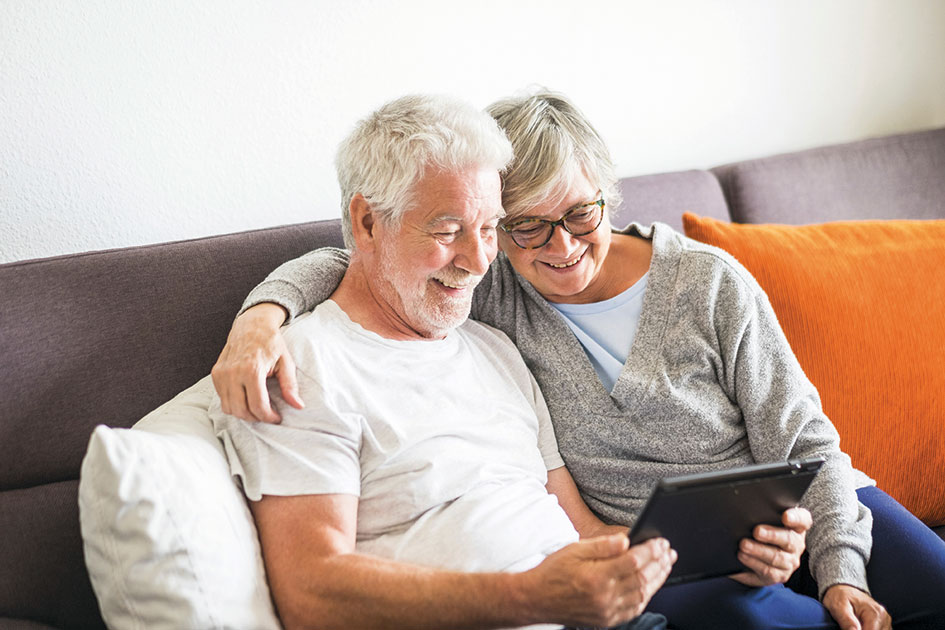 Cheerful couple on comfy sofa looking at a tablet device together