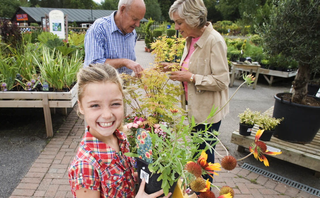 Grandparents with granddaughter in garden.