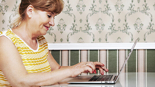 Woman smiling while sat typing on laptop