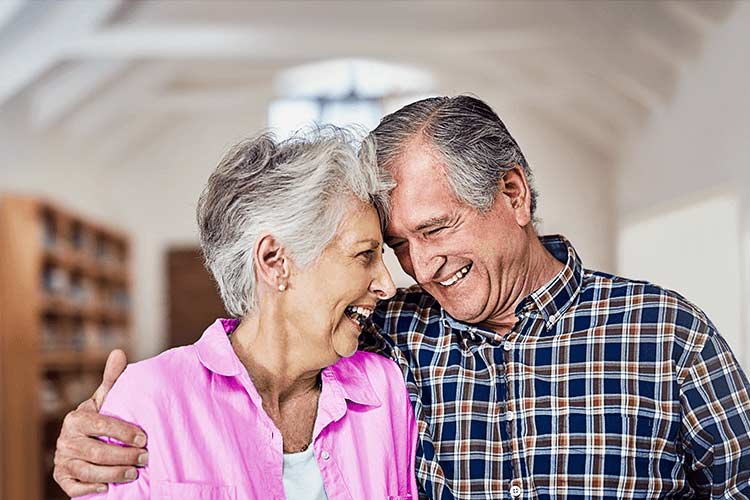 Over 50s couple hugging and laughing.