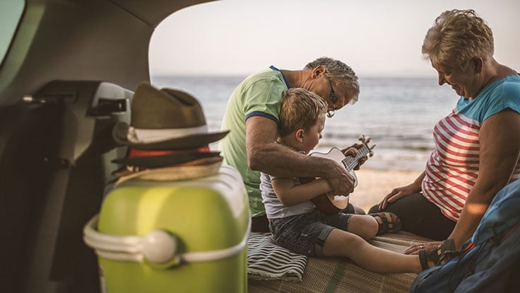 Grandparents smiling with granddaughter on beach