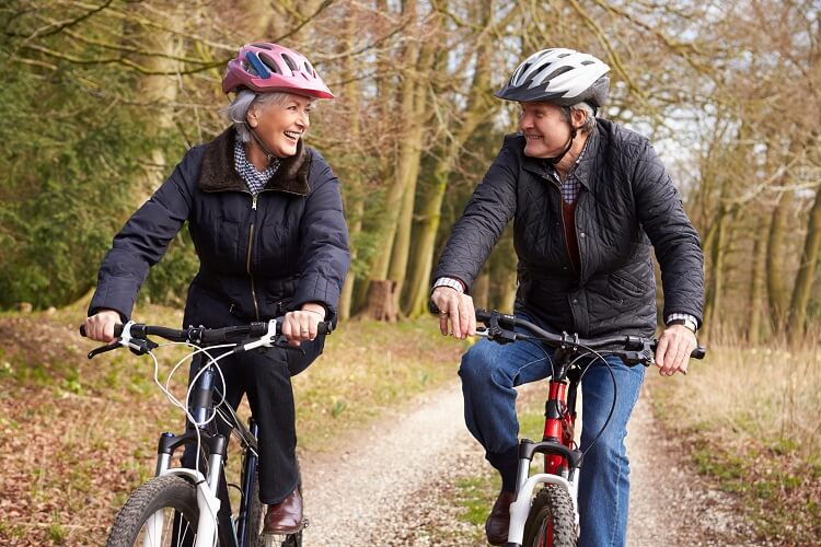 Retired man and woman exercising on bicycles outdoors