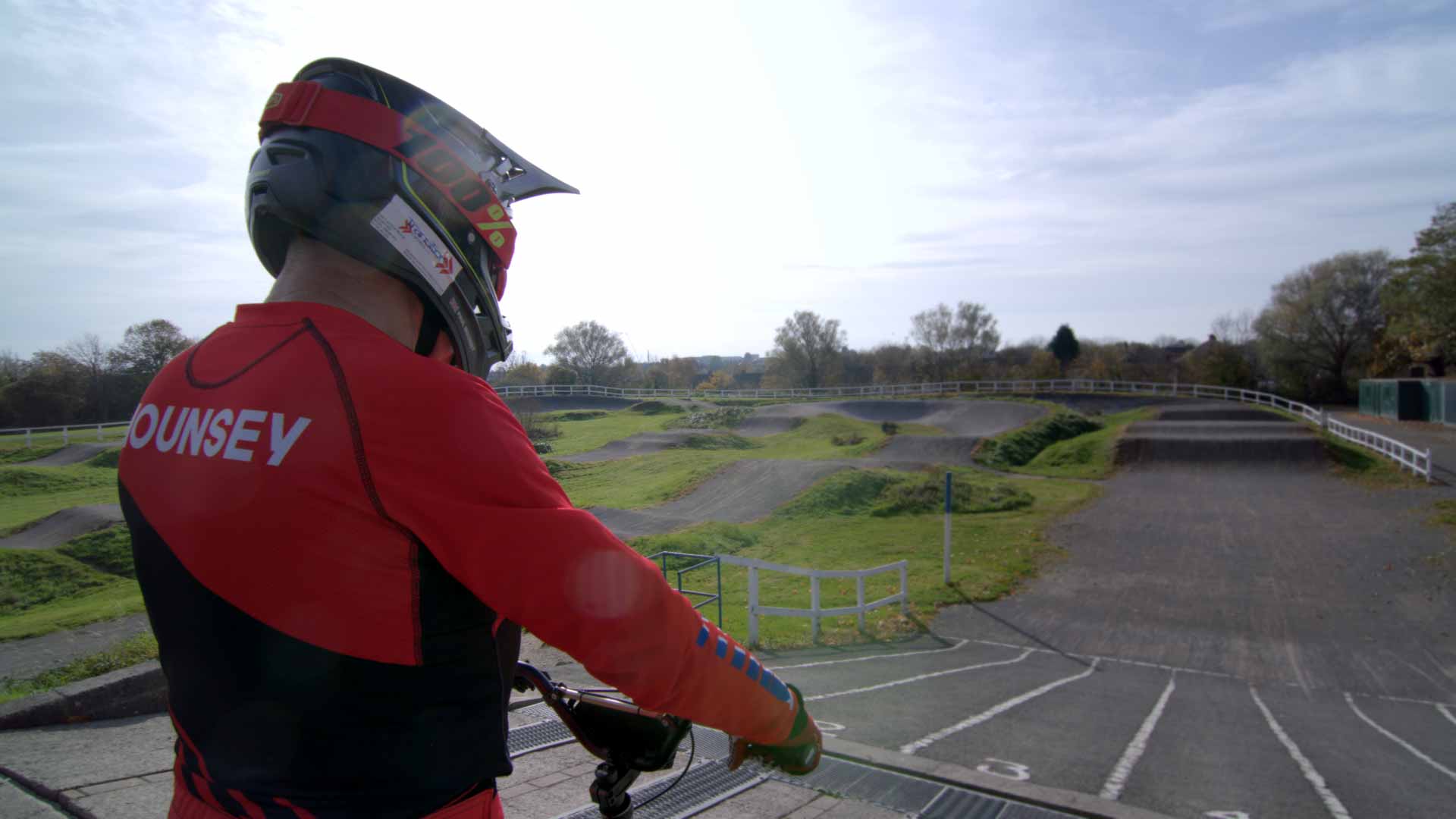 Paul Mounsey sat on his BMX at the start of a race track in full race gear.